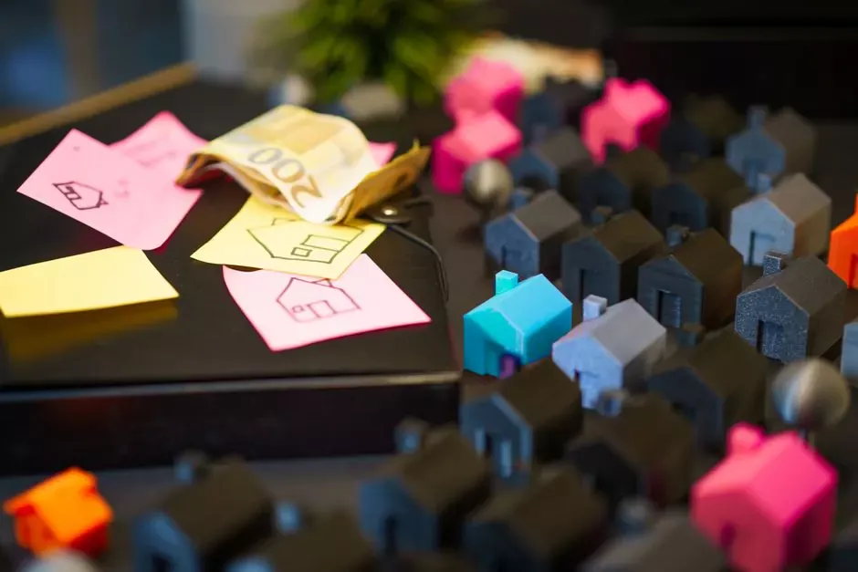 Colorful model houses next to Euro notes and sketches, showcasing real estate investment planning.